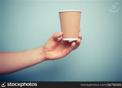 A man is holding a brown paper cup