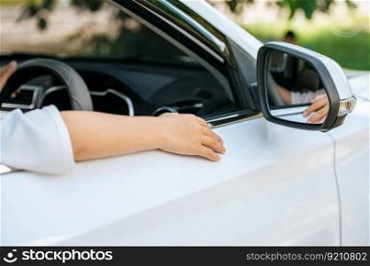 A man is holding a steering wheel in a car and his hand rests on the edge of the door.