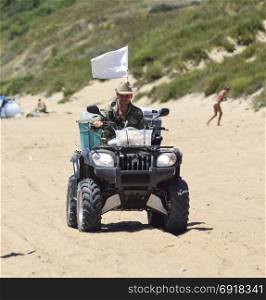 A man is riding a quad bike along the sandy beach of the sea.. Anapa, Russia - July 17, 2015: A man is riding a quad bike along the sandy beach of the sea.