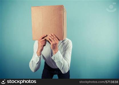 A man is standing around with a cardboard box on his head