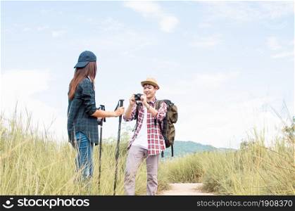 A man is taking photos for his asian girlfriend while traveling and climbing the mountains in summer time