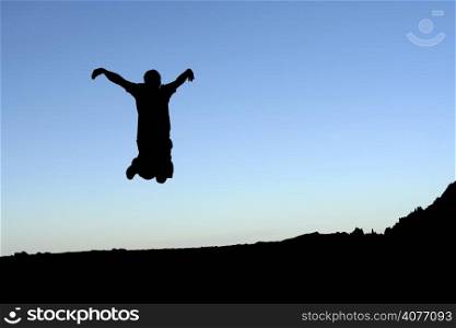 A man jumping in the air, in silhouette