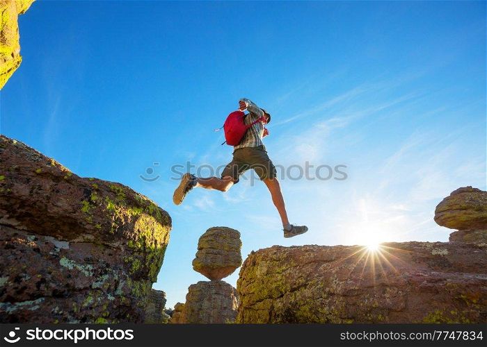 a man jumps between cliffs in the mountains