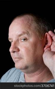 A Man Listening by cupping his ear with his hand.