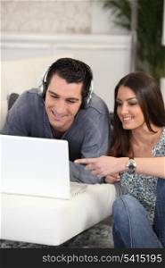a man listening music on computer with his wife