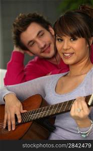 a man looking a woman playing guitar