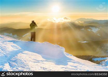A man looking at sun and beautiful sunset in winter mountains with snow. A man looking at beautiful sunset