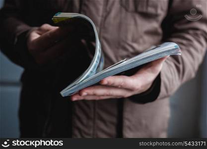 A man looks at a magazine. Press hands.