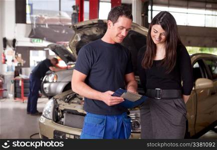 A man mechanic and woman customer discussing repairs done to her vehicle