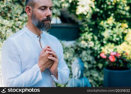 A man meditates outdoors and keeps hands together in a prayer position. . Man meditating Outdoors and keeping hands together in a prayer position.