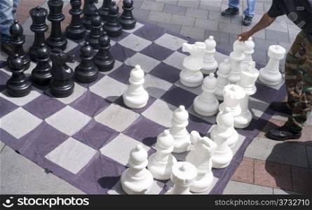 A man moves his Giant Bishop in a game of chess on the street