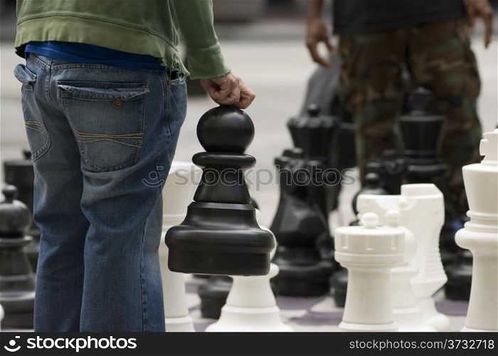 A man moves his Giant Pawn in a game of chess on the street