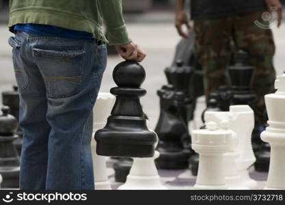 A man moves his Giant Pawn in a game of chess on the street