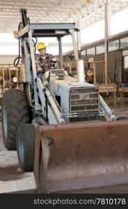 A man on a construction site driving a backhoe loader.