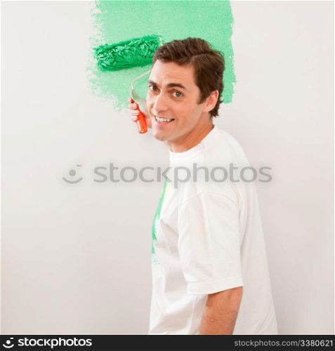 A man paiting a wall with a roller brush