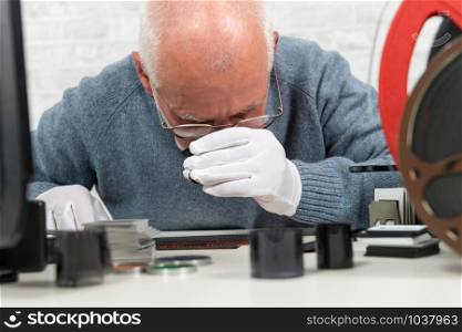 a man photographer looking at negative film with a magnifying glass