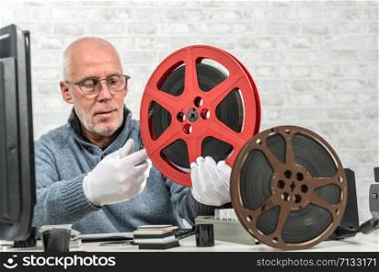 a man photographer looking at reel 16mm film