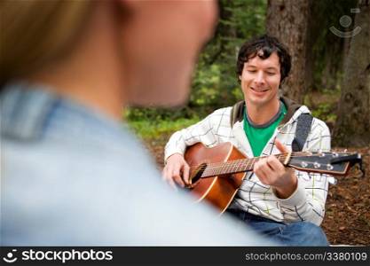 A man playing a guitar and singing for a woman