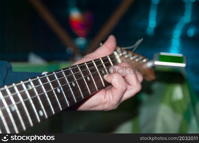 A man plays a white electric guitar