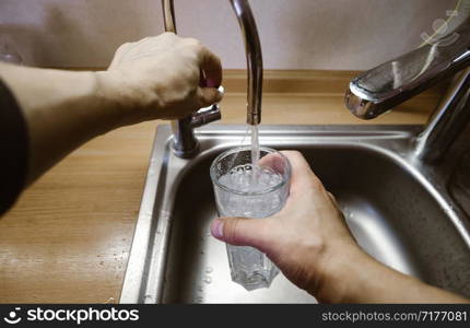 A man pours a glass of water from the tap. Wide angle first person view