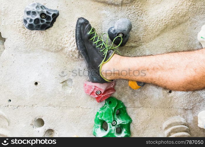 A Man practicing rock climbing on artificial wall indoors. Active lifestyle and bouldering concept.