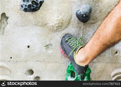 A Man practicing rock climbing on artificial wall indoors. Active lifestyle and bouldering concept.