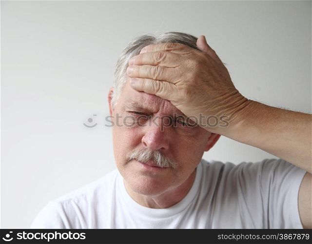 A man puts his hand to his forehead in pain.