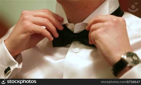 A man puts on bow tie