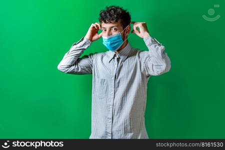 A man putting on the mask on isolated background, Handsome man putting on a surgical mask isolated. Concept of a person correctly putting on a surgical mask isolated