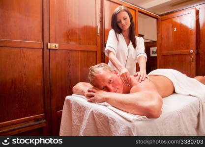 A man receiving a shoulder massage in an 1930&rsquo;s styled spa