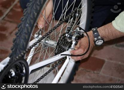A man repairing the wheel of a bicycle with the hands and one adjustable spanner