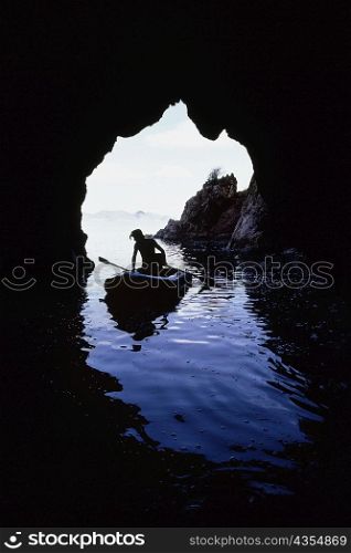 A man rowing a canoe seen through the cave, Treasure Island, Virgin Islands