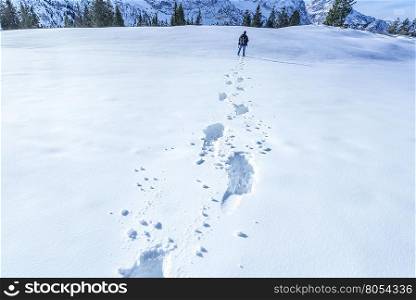 A man&rsquo;s footprints on the snow - Winter scenery with lots of snow, a man heading to the mountains, leaving footsteps behind.