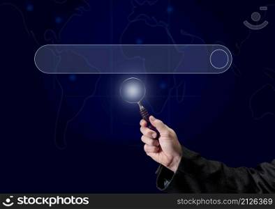 a man&rsquo;s hand holds a magnifying glass on the background of a template for entering and searching information on the Internet. Globalization, availability of information