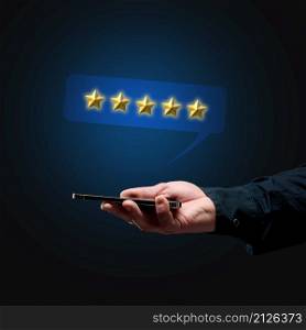 a man&rsquo;s hand holds a smartphone and five gold stars above it. App evaluation. User reviews