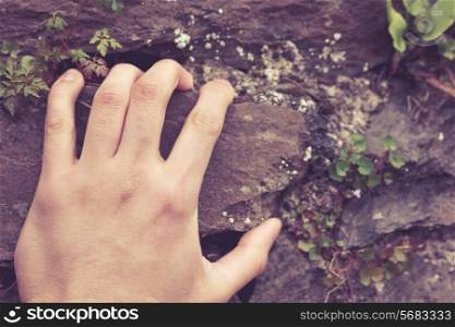 A man&rsquo;s hand is grabbing onto a rock