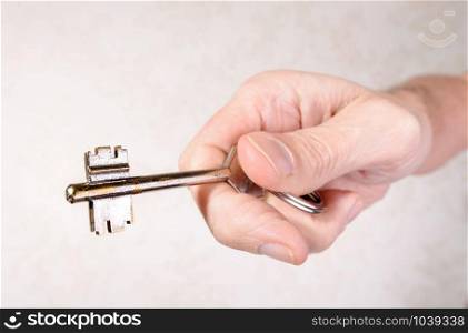 A man&rsquo;s hand is holding a key, opening or closing a door, on light background