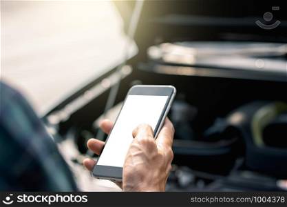 A man's hand is using a smartphone on a traffic road while a car crashes.