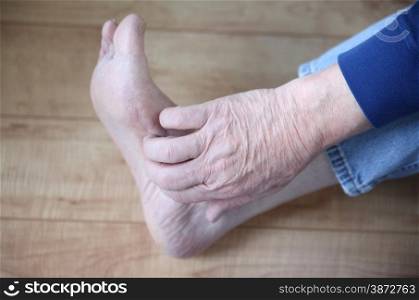 a man&rsquo;s hand on his itchy foot