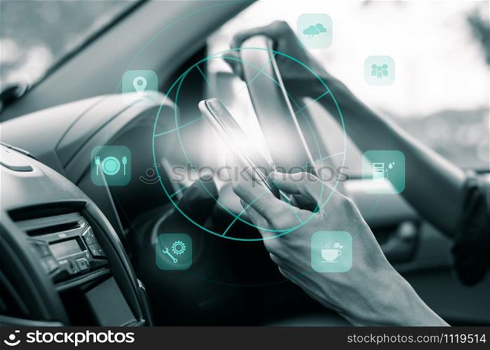 A man&rsquo;s hand uses a smartphone while driving, and has an icon for technology that can be used while traveling.