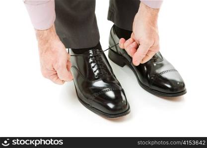 A man&rsquo;s hands tying the laces on a new pair of dress shoes. Isolated on white.