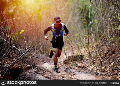 A man Runner of Trail and athlete&rsquo;s feet wearing sports shoes for trail running in the forest