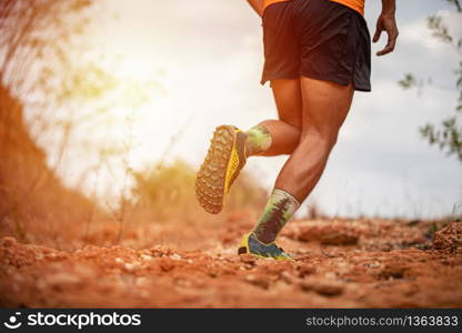 A man Runner of Trail and athlete&rsquo;s feet wearing sports shoes for trail running in the mountain