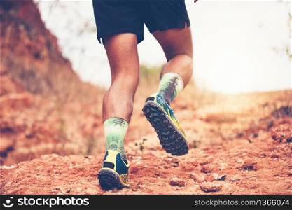 A man Runner of Trail . and Close up of an athlete&rsquo;s feet wearing sports shoes for trail running in the mountains