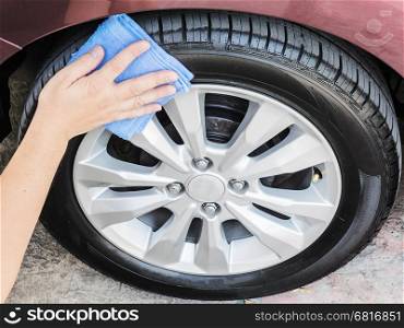 A man's hand is cleaning and waxing tire of car