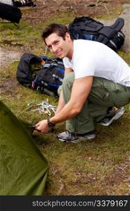 A man setting up a tent on a camping trip