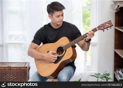 A man sitting and playing guitar on a chair