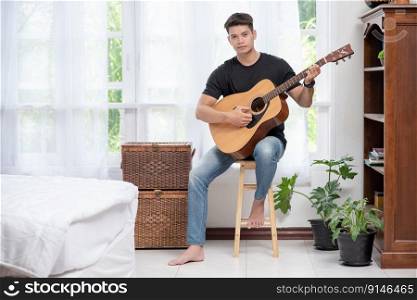 A man sitting and playing guitar on a chair