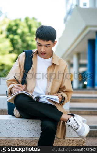 A man sitting and reading a book on the stairs.