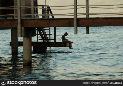 A man sitting on steps of a pier, Moorea, Tahiti, French Polynesia, South Pacific